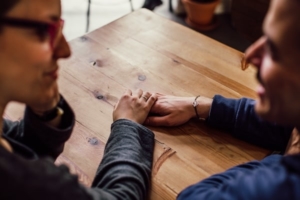 couple holing hands on wooden table